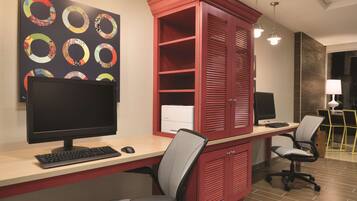 A modern office with a desk, two chairs, a computer monitor, and a red cabinet.