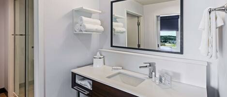Een moderne badkamer met een glazen douche, een witte wastafel en een grote spiegel.