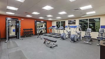Un gimnasio con cintas de correr, elípticas y pesas libres.
