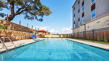 Een buitenzwembad, ligstoelen bij het zwembad