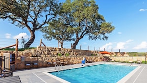Une piscine rectangulaire bordée d’un mur en pierre et entourée de chaises longues.