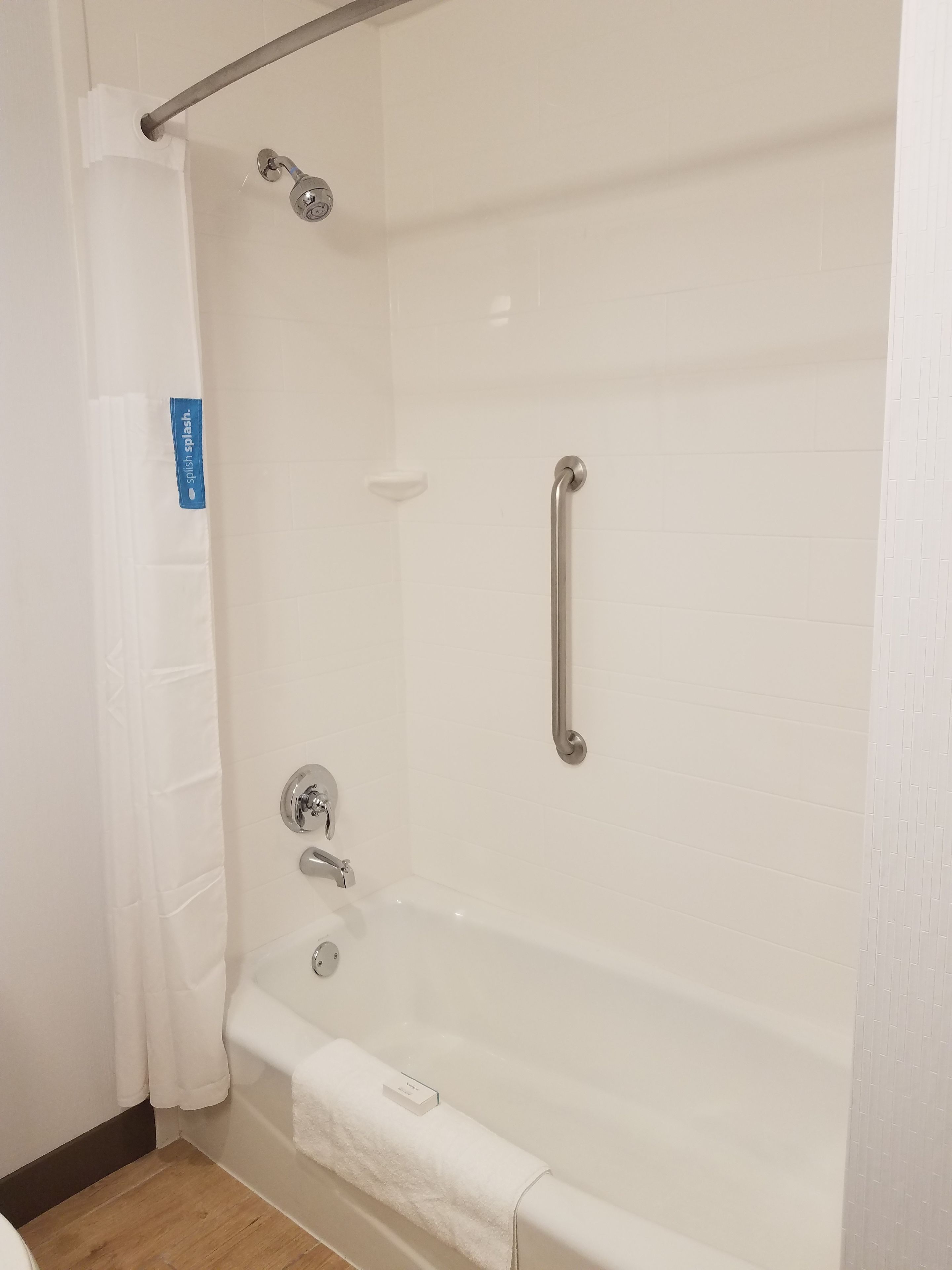 A modern bathroom with a bathtub, grab bars, and a shower curtain.