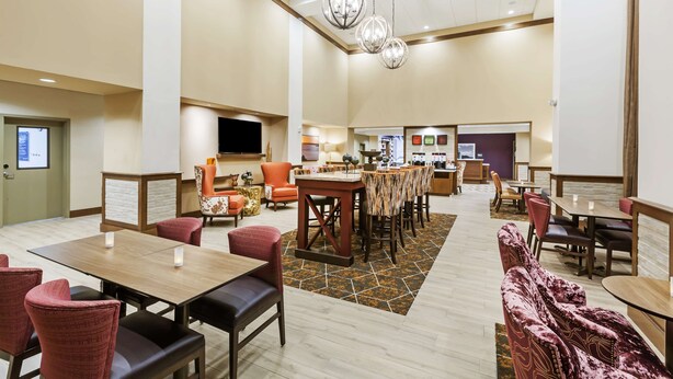 Un hall d’hôtel comprenant différents espaces de détente, un bar et un écran de télévision.