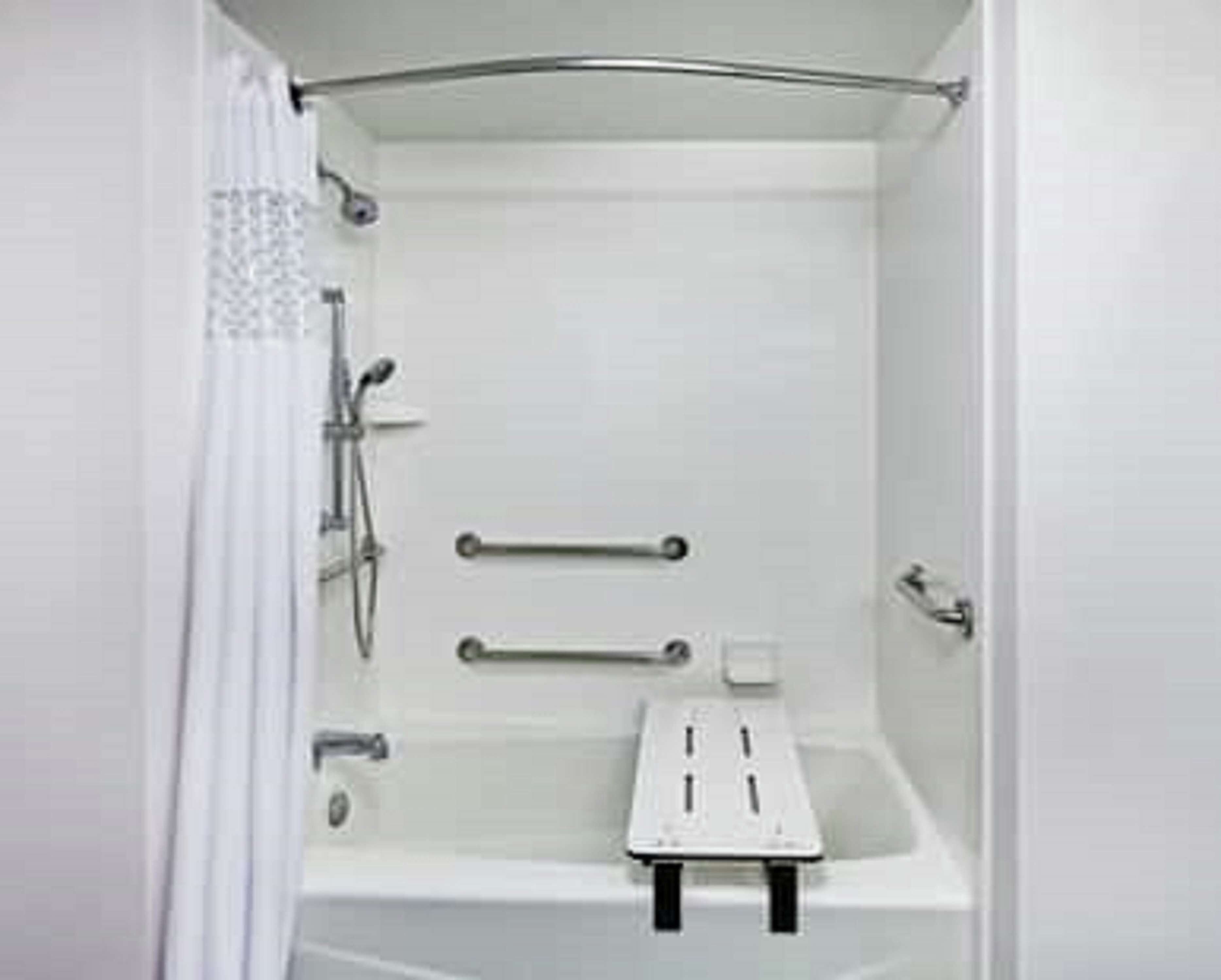 Une cabine de douche blanche équipée d’un pommeau de douche à main, d’un flexible de douche et d’une brosse à main.