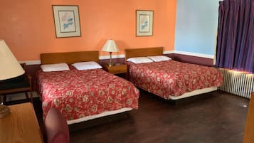 A hotel room with two beds, a nightstand, a lamp, and framed pictures on the wall.