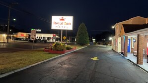 A Royal Inn Motel sign, a gas station, and a brick building with a blue door.