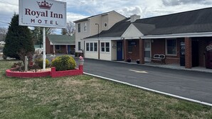 A Royal Inn Motel with a signboard, a parking lot, and a building with a blue door and an office.