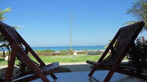 Two wooden lounge chairs facing a beach with a clear view of the ocean. - Casa na Beira da Praia de Geribá (Búzios)