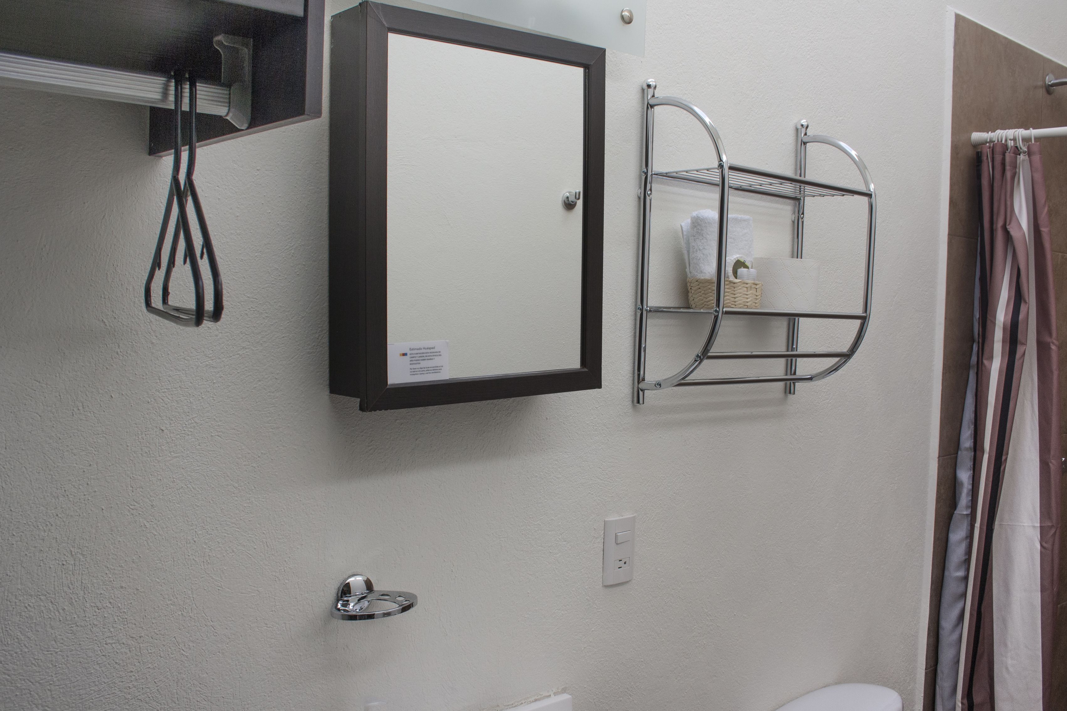 A bathroom with a white sink, a mirror, a towel rack, and a shower curtain.