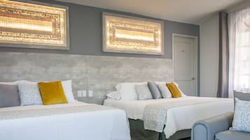 A hotel room with two beds, a grey accent wall, and a window with sheer curtains.