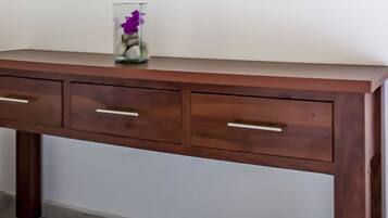 Un escritorio de madera con tres cajones y un jarrón con flores encima.