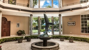 Un atrium à plusieurs niveaux, doté d’une fontaine centrale, de colonnes et de plantes en pot.