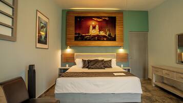 Una camera d'albergo con un letto grande, una testiera con pannello in legno, un comodino, una scrivania e una sedia.