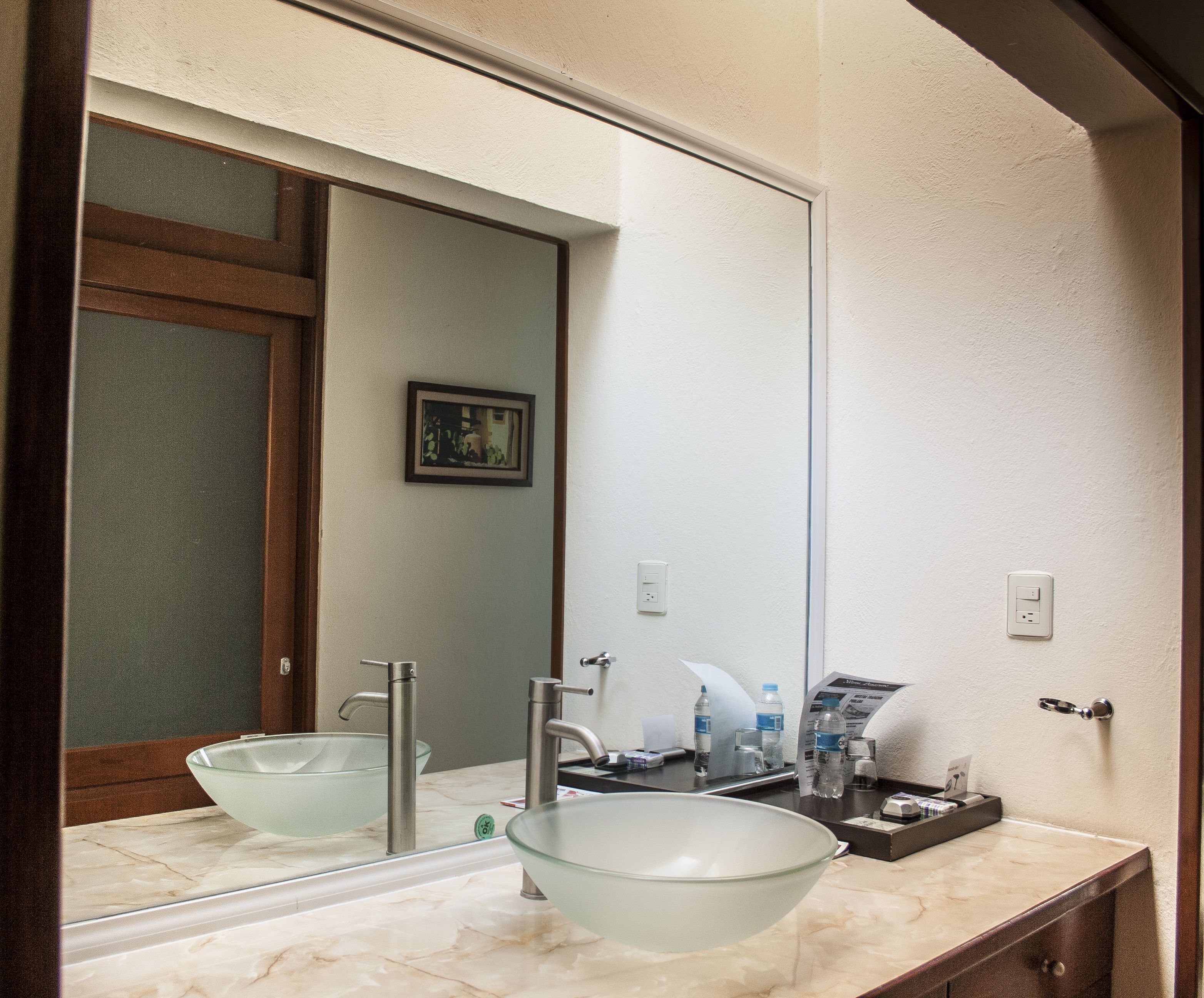 A bathroom with a glass bowl sink, a mirror, and a marble countertop.