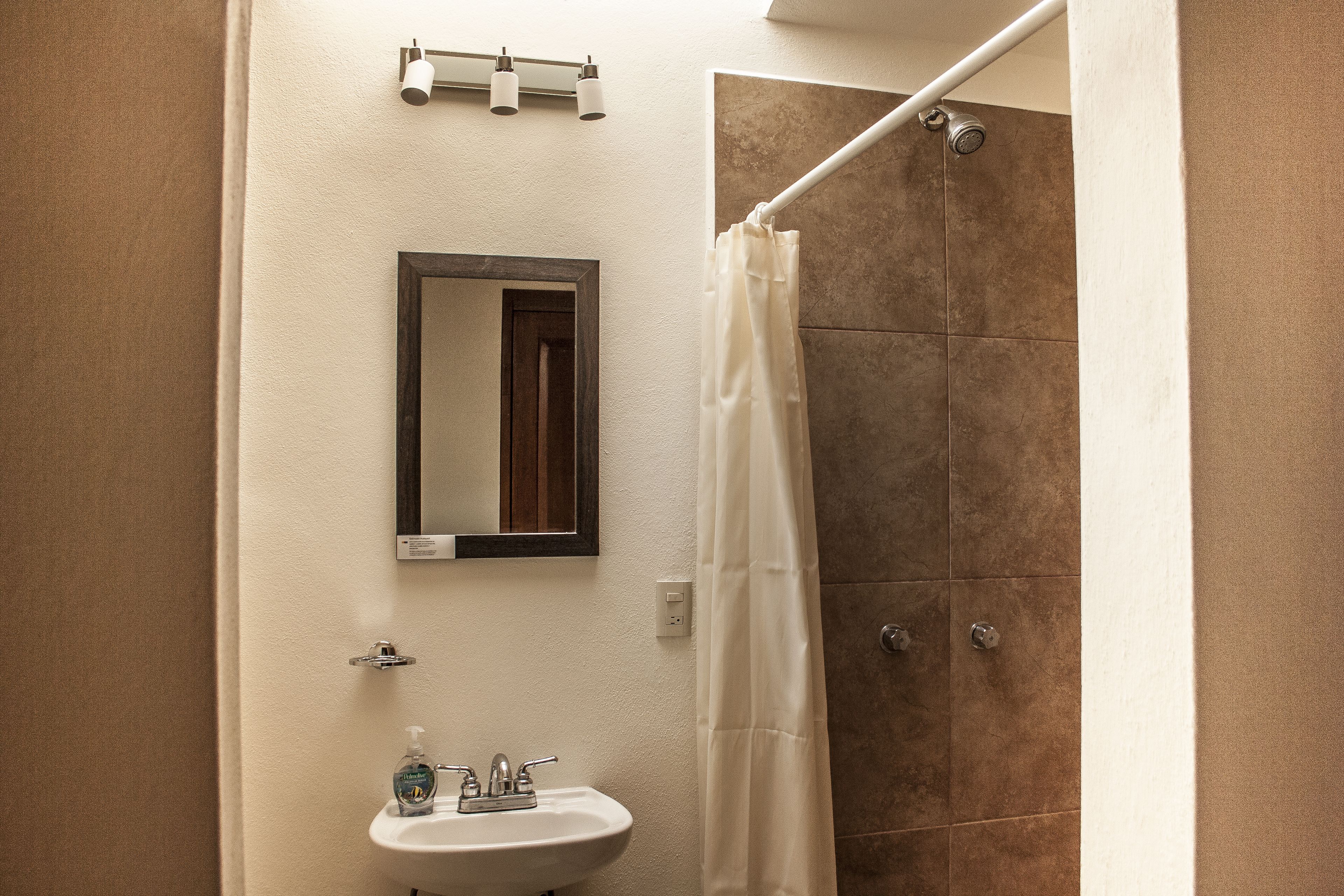 A bathroom with a sink, mirror, and shower curtain.