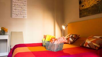 Habitación de hotel con una cama grande, una lámpara de noche, una obra de arte en la pared y una mesita con un jarrón de flores.