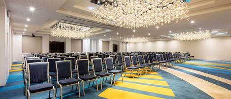 A conference room with rows of chairs, a patterned carpet, and a large chandelier.