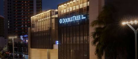 Un moderno edificio de hotel con un llamativo letrero de 'DoubleTree by Hilton', con fachada de vidrio y un diseño contemporáneo y estructurado.