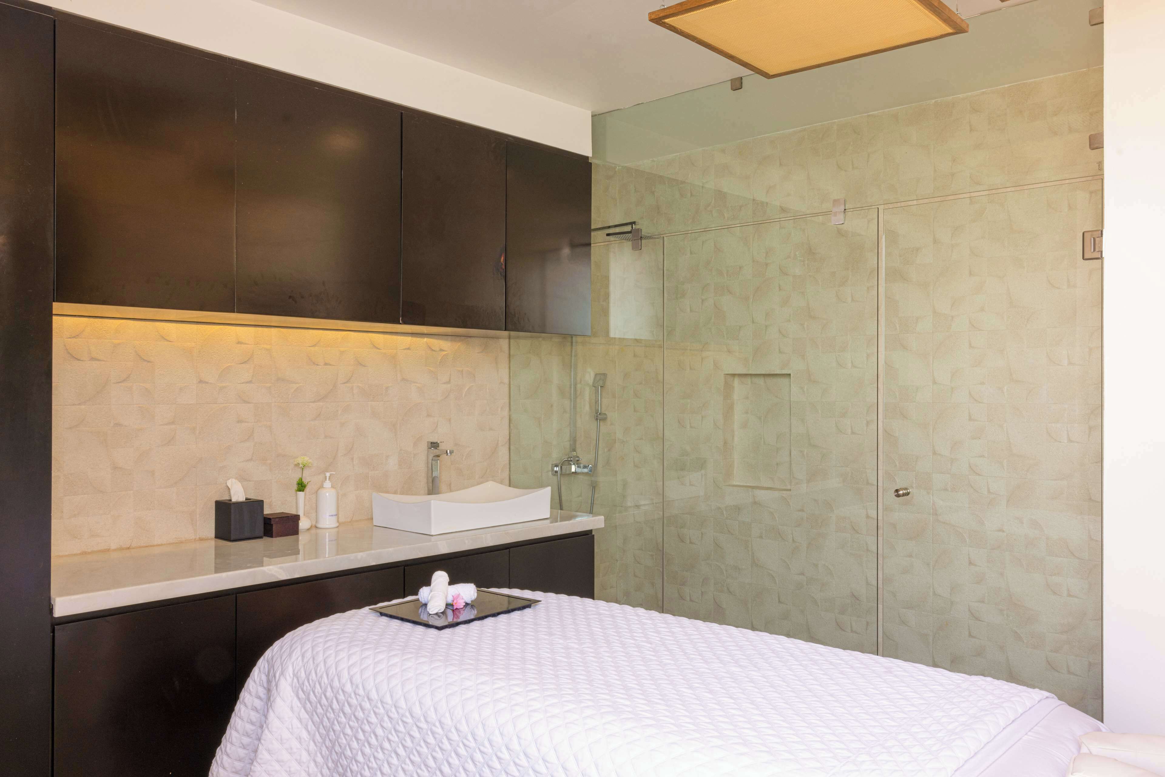 Un baño moderno con un espejo grande, cabina de ducha de vidrio y lavamanos blanco.