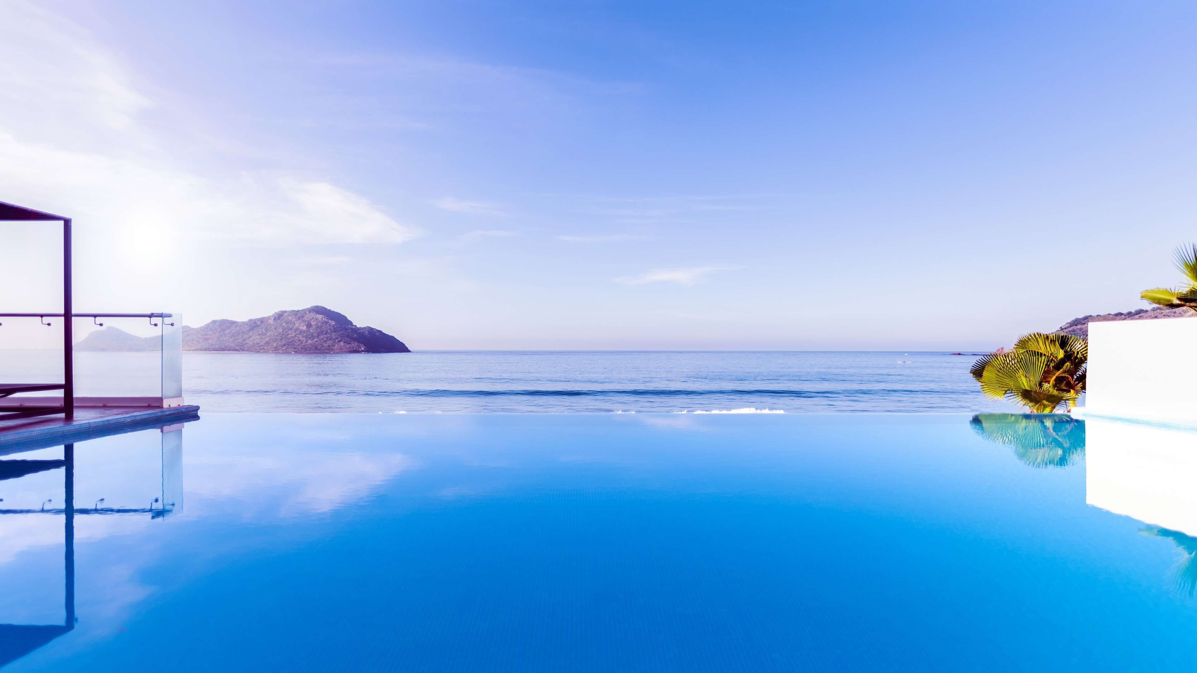 An infinity pool with a clear view of the sea and a distant island.