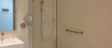A modern bathroom with a glass-enclosed shower, a sink with a mirror, and a towel rack.