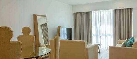 Una sala de estar moderna con una mesa de vidrio, sofás color beige y un espejo grande.