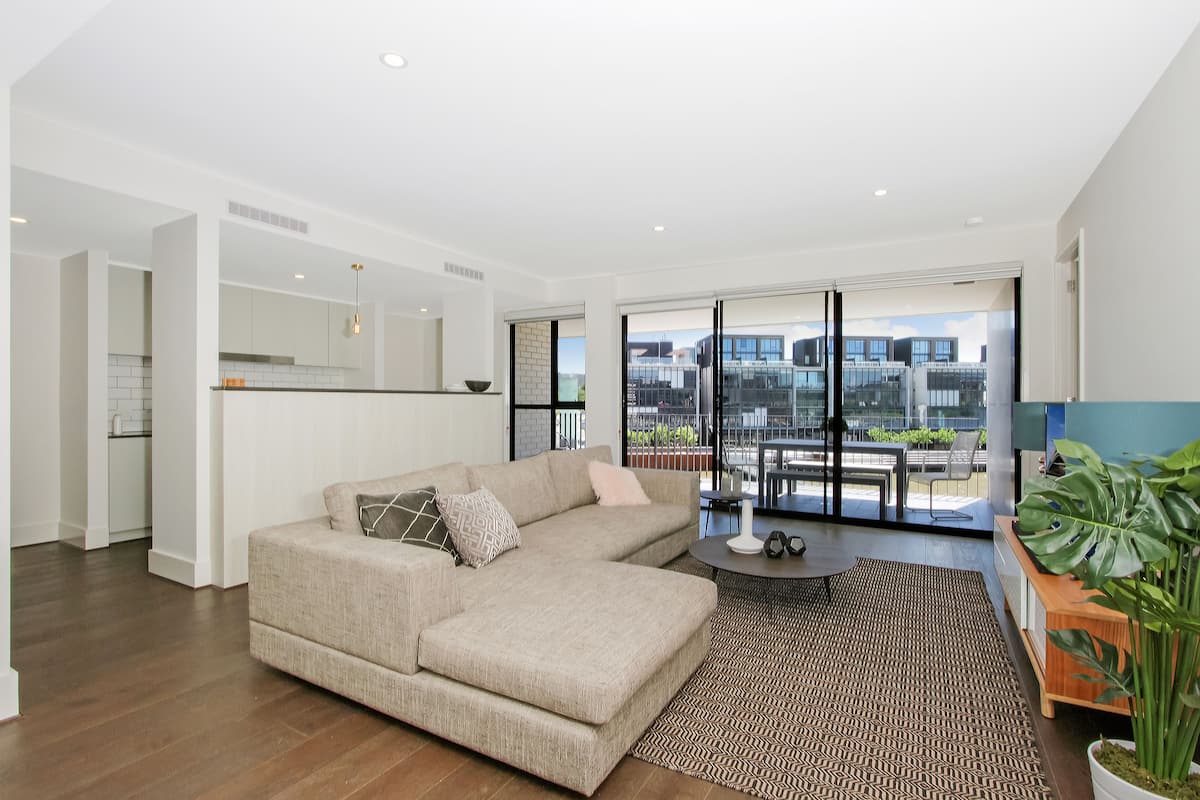 A modern living room with a sectional sofa, a coffee table, and a large window offering a city view.