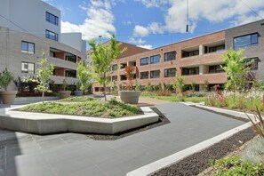 A courtyard with a central garden, surrounded by multi-story buildings with large windows and balconies. - Accommodate Canberra - The Prince (Kingston)