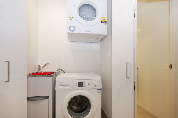 Ein kleiner Hauswirtschaftsraum mit einer Waschmaschine mit Frontlader und einem Waschbecken.