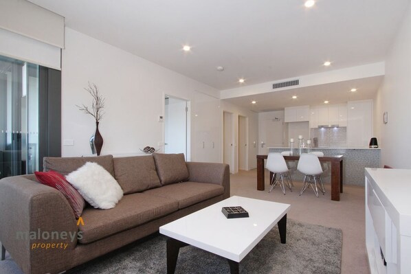 A modern living room with a sofa, a coffee table, and a dining area with chairs.