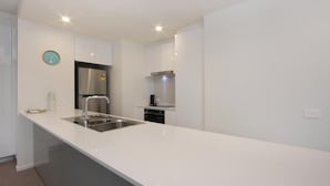 Uma cozinha moderna com armários brancos, uma pia de aço inoxidável e um forno embutido.
