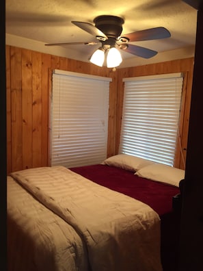 A bedroom with two beds, wooden walls, and a ceiling fan. - Treetop Cabin (Auberry)