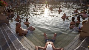 A communal hot spring area with people relaxing in the water.