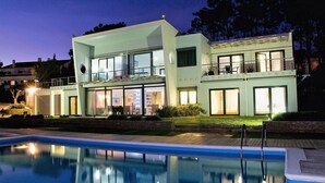A modern two-story house with a swimming pool in front.