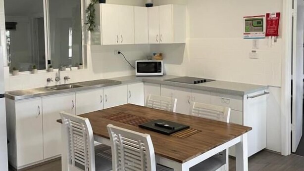 Una cocina moderna con armarios blancos, una mesa de comedor de madera y un microondas.