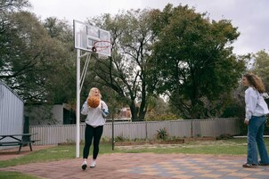 Una cancha de baloncesto al aire libre con un aro, una mesa de picnic y un área cercada con árboles.