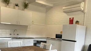 Una cocina moderna con armarios blancos, una mesa de comedor de madera y un sofá negro.