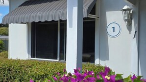 Un edificio con fachada blanca, un cartel con el número 1 y un acceso cubierto.