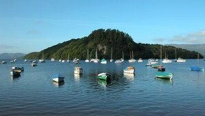 A calm harbor with several small boats anchored near a forested island. - Magnificent Family House with Stunning Private Garden (Drymen)