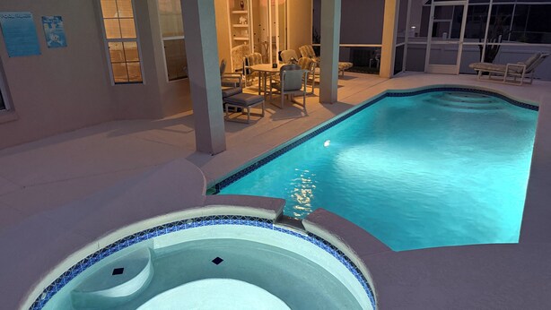 A swimming pool with a hot tub, lounge chairs, and a covered patio area. - Villa With Private Pool And Jacuzzi, Ideally Situated for Disney (Clermont)