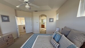 A bedroom with a large bed, a ceiling fan, a dresser, and a door leading to another room. - Villa With Private Pool And Jacuzzi, Ideally Situated for Disney (Clermont)