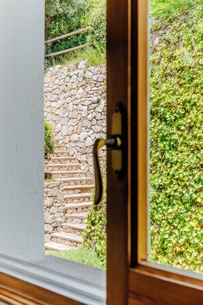 A stone staircase leading outside, a wooden door with a brass handle, and a view of greenery.