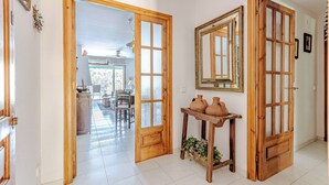 Un couloir avec des portes en bois, un miroir et une table sur laquelle sont posées des objets en céramique.