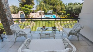 A balcony with two wicker chairs and a table, overlooking a pool and garden. - Villa Ferradina 4+2, Emma Villas (Ispica (Ragusa))