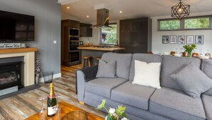 A modern living room with a grey sofa, a wooden coffee table, and a fireplace. - Stunning Lodge set in relaxing surrounding, sleeps 6/8, 3 en-suites, free WIFI (Windermere)