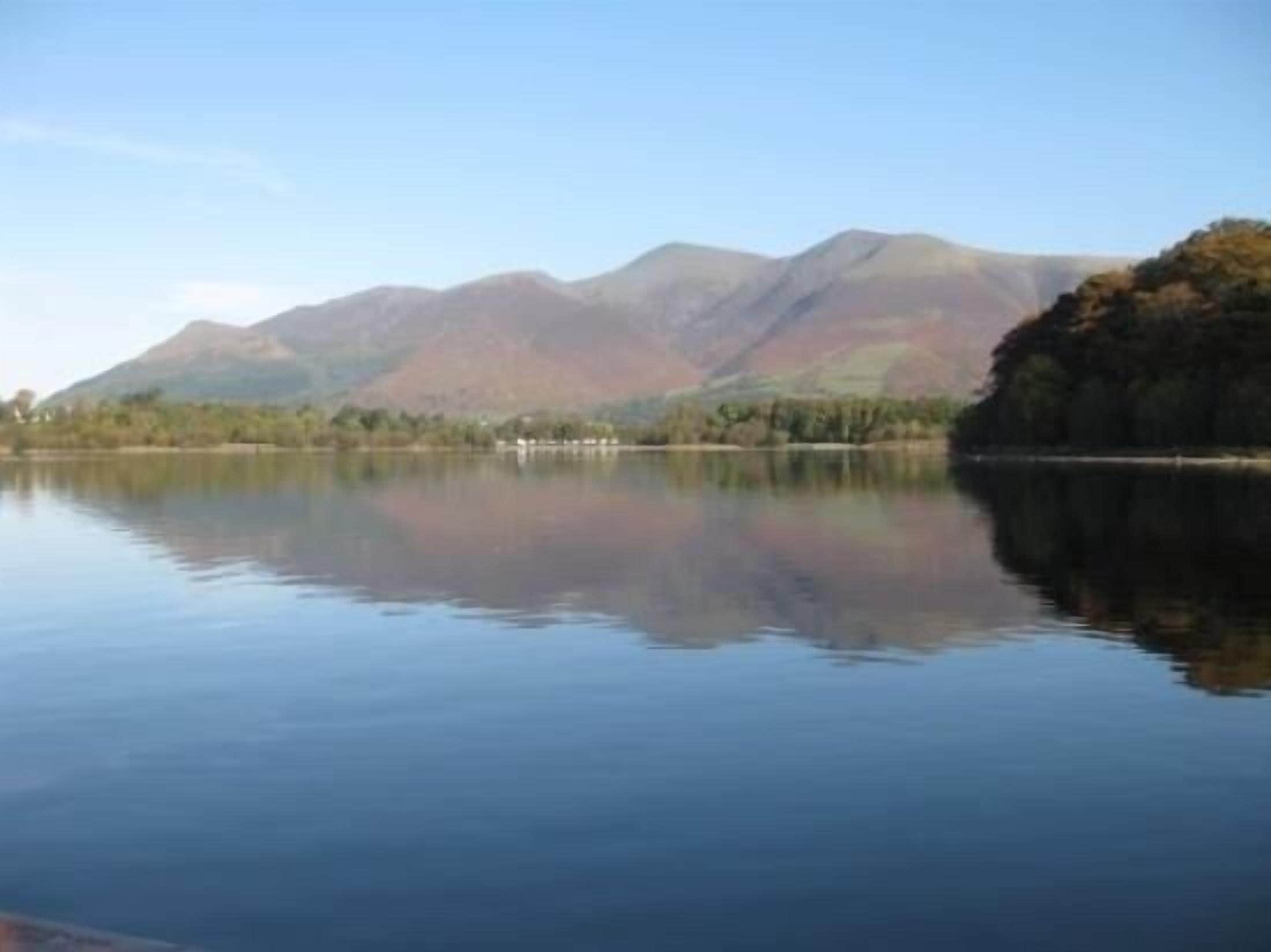 A calm lake with mountains in the background.
