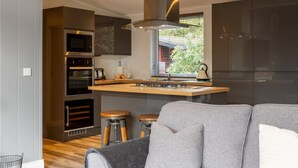 A modern kitchen with a central island, built-in appliances, and a large window. - Stunning Lodge set in relaxing surrounding, sleeps 6/8, 3 en-suites, free WIFI (Windermere)