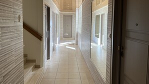 A hallway with a patterned wall, a wooden ceiling, and a tiled floor.