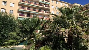 A multi-story residential building with balconies, surrounded by palm trees.
