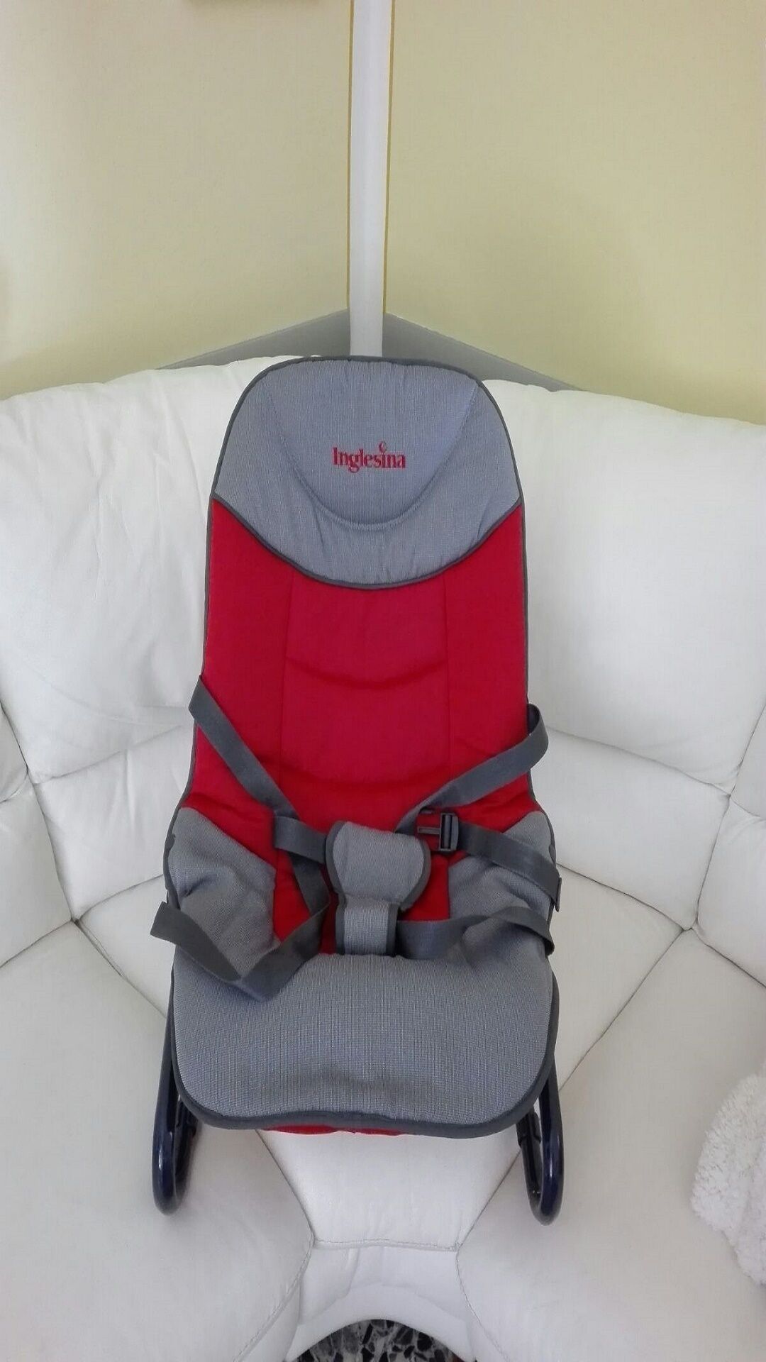 A red and grey baby car seat on a white couch.